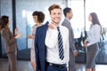 Confident businessman looking at camera while her colleagues discussing in background Royalty Free Stock Photo