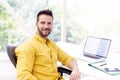 Confident businessman looking at camera and smiling while sitting at office desk Royalty Free Stock Photo