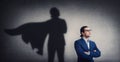 Confident businessman looking determined as casting a powerful superhero shadow on the wall. Motivated and ambitious business Royalty Free Stock Photo