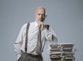 Confident businessman posing with a pile of paperwork