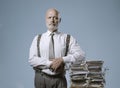 Confident businessman posing with a pile of paperwork