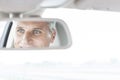 Confident businessman reflecting in rear-view mirror of car