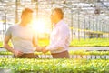 Confident businessman shaking hands with male botanist in greenhouse