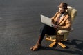 confident businessman sitting in armchair and using laptop Royalty Free Stock Photo