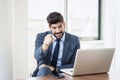 Confident businessman sitting behind his laptop and pointing at camera Royalty Free Stock Photo