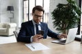 Confident businessman wearing glasses using phone and laptop, working online Royalty Free Stock Photo