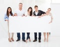 Confident businesspeople holding blank billboard Royalty Free Stock Photo