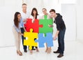 Confident businesspeople joining puzzle pieces Royalty Free Stock Photo