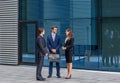 Confident businesspersons talking in front of modern office building. Businessmen and businesswoman have business