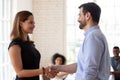 Confident businesswoman and businessman shaking hands at meeting