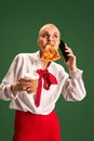 Confident businesswoman with pizza slice holding in one hand coffee and have phone call against green studio background. Royalty Free Stock Photo