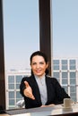 Confident businesswoman smiling at camera in office with cityscape view Royalty Free Stock Photo