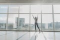 Confident woman spreading hands standing at office window, enjoying big city, successful entrepreneur celebrating business success