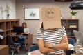Woman wearing happy face cardboard in office