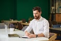 Confident, busy male entrepreneur with laptop, making notes, while sitting at table in restaurant. Royalty Free Stock Photo