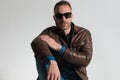 Confident casual man wearing brown leather jacket and sunglasses and posing Royalty Free Stock Photo