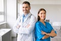 Confident caucasian colleagues male doctor and female nurse, wearing coats, posing with folded arms, smiling at camera Royalty Free Stock Photo