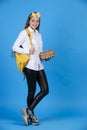 Confident caucasian female student with backpack posing, while standing with crossed legs in studio. Royalty Free Stock Photo