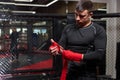 Confident Caucasian Male Kickboxer Fighter Preparing For Fight, Wrapping Hand In Red Bandage