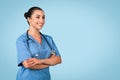 Smiling woman nurse in teal scrubs with arms folded