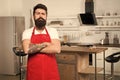 Confident chef. Restaurant or cafe cook. Mature male. Bearded man cook. Hipster in kitchen. Bearded man in red apron Royalty Free Stock Photo