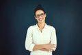 Confident and content. Portrait of a confident young businesswoman standing with her arms folded in the studio. Royalty Free Stock Photo