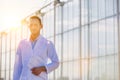 Confident crop scientist wearing lab coat and holding report in greenhouse