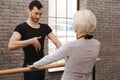 Confident dance teacher instructing elderly woman in the dance studio