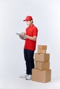 Confident deliveryman. Cheerful young deliveryman holding a cardboard box while standing in front of the box stack