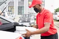 Confident deliveryman in red uniform puts orders in the car