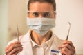 Portrait of confident dentist wearing surgical mask and eyewear while holding dental equipments Royalty Free Stock Photo