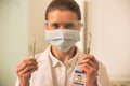 Portrait of confident dentist wearing surgical mask and eyewear while holding dental equipments Royalty Free Stock Photo