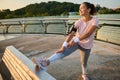 Confident happy African American athletic woman in sportswear, wearing headphones, standing on a treadmill, putting her legs on a Royalty Free Stock Photo