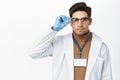 Confident doctor in glasses, looking serious and determined, standing in medical robe against white background