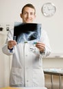 Confident doctor in lab coat examining x-ray