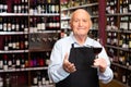 Confident elderly male winemaker inviting to wine house, offering glass of wine for tasting Royalty Free Stock Photo