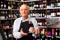 Confident elderly male winemaker inviting to wine house, offering glass of wine for tasting