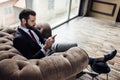confident elegant businessman using smartphone and sitting