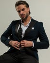 confident elegant man with open collar shirt unbuttoning tuxedo
