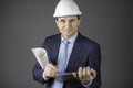 Confident engineer in hard hat with clipboard and blueprint roll looks at camera Royalty Free Stock Photo