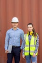 Confident engineers portrait in uniforms standing in front of the containers. Logistics and shipping. Professional occupation Royalty Free Stock Photo