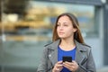 Confident entrepreneur holding phone looks at side