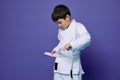 Confident European teenage boy puts on white kimono, ties a belt around his waist, ready for combat sports. Aikido fighter. Royalty Free Stock Photo