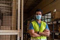 Confident factory warehouse worker wearing a protective face mask while working in logistic industry having arms crossed