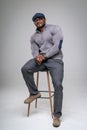 Confident fashionable man sitting on a chair at studio. Handsome athletic boy keep posing for camera.