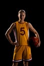 Confident female basketball player poses with a ball on a black background Royalty Free Stock Photo