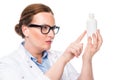 confident female doctor in eyeglasses pointing at pill bottle