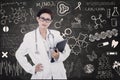 Confident female doctor hold e-tablet on written blackboard