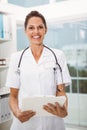 Confident female doctor holding clipboard in medical office Royalty Free Stock Photo