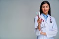 Confident female doctor with a phonendoscope in a white medical coat shows toothbrush and toothpaste in hand. Dental concept